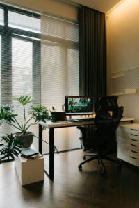 A stylish home office featuring a sleek desk, ergonomic chair, and potted plants under natural light.